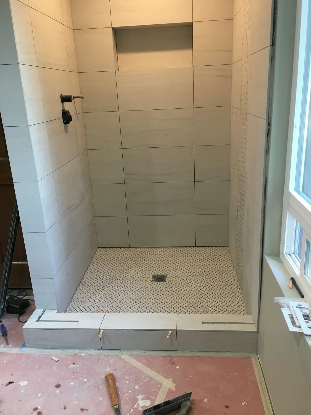 Shower with light tile and herringbone floor