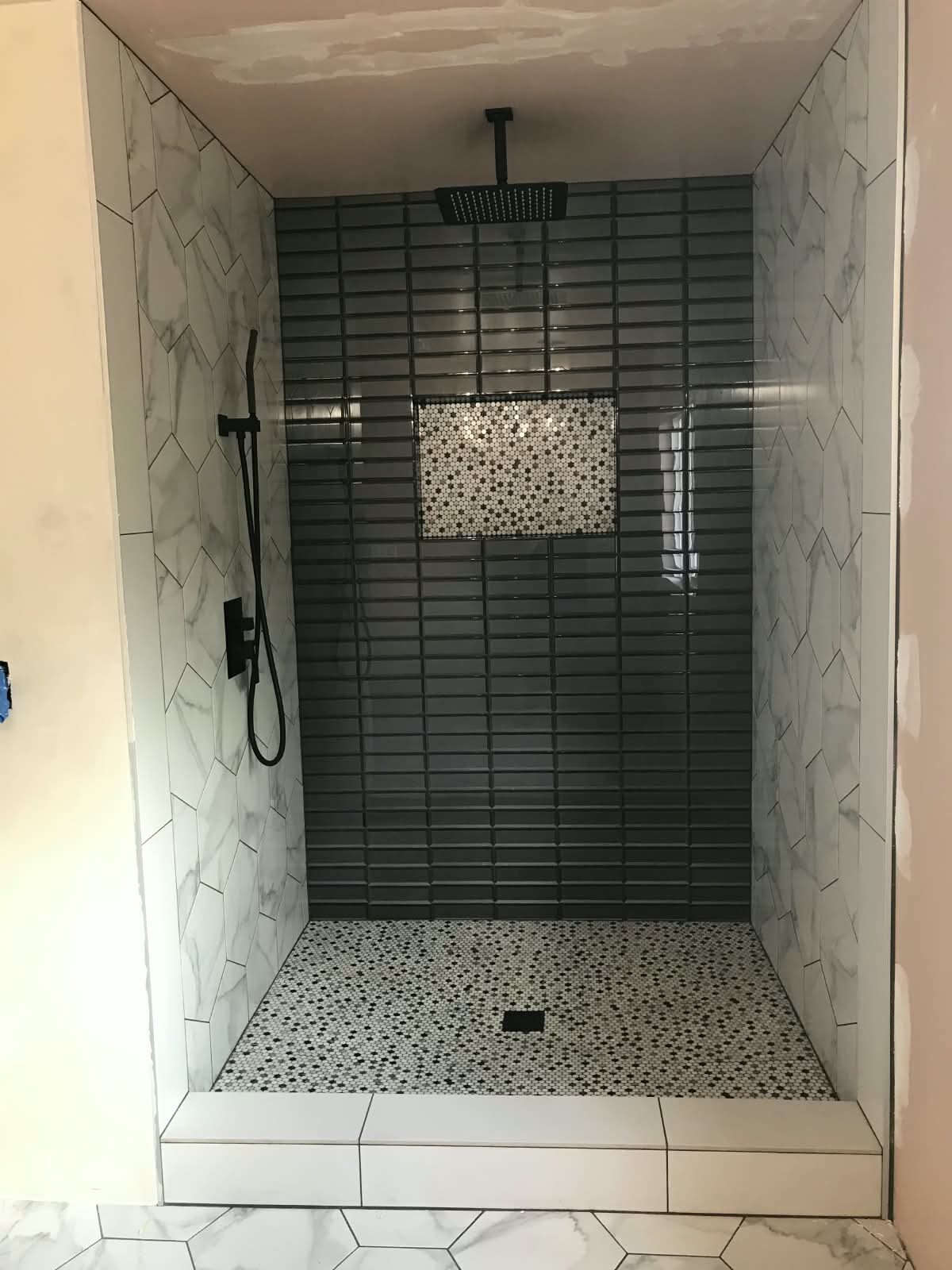 Shower with dark gray tile and mosaic floor